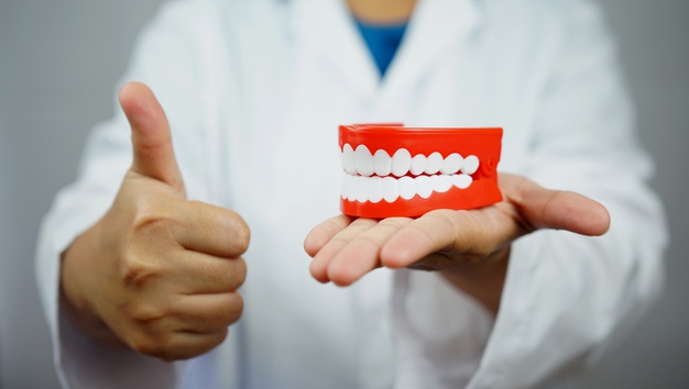 female-dentist-holding-denture-giving-thumb-up-dental-blog