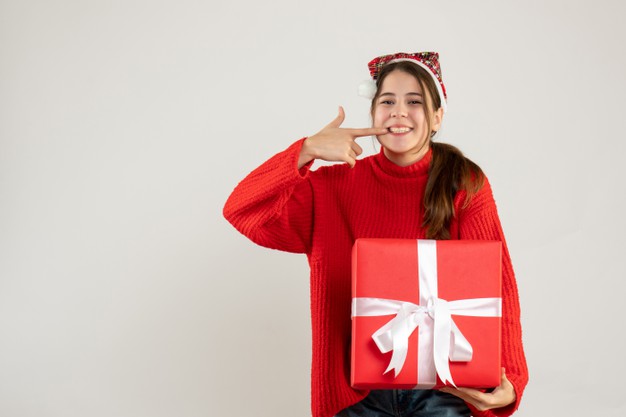 happy-cute-girl-holding-heavy-gift-pointing-her-teeth-standing-white